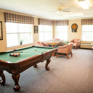 A cozy game room featuring a pool table and comfortable seating areas with large windows.