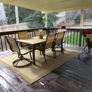A cozy covered patio with a table and chairs set on a wooden deck.
