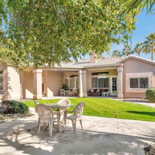 A serene backyard with a patio set, well-kept lawn, and shaded by trees.