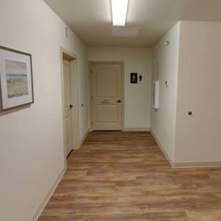A well-lit hallway with wooden flooring and multiple doors.