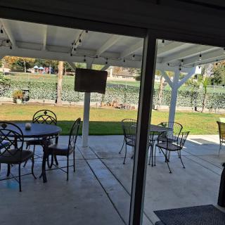 A covered patio with outdoor seating overlooking a well-maintained backyard and lawn.