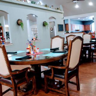 A cozy dining room with elegant chairs and a round wooden table, accented by homey decor and warm lighting.
