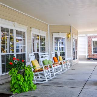 A cozy porch with rocking chairs and vibrant pillows, adorned with lush plants.