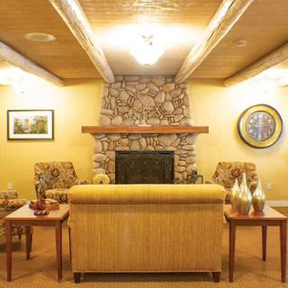 A cozy living room featuring a stone fireplace, comfortable seating, and warm lighting.