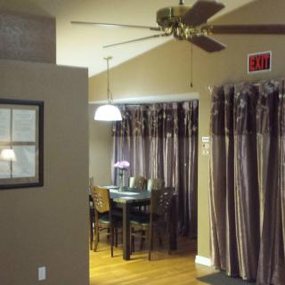 A cozy dining area with a ceiling fan, curtains, and a hanging light fixture over the table.