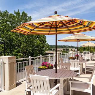 A sunny outdoor patio with tables, chairs, and colorful umbrellas.