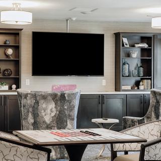 A modern living room with comfortable seating, a large television, and decorative shelves.