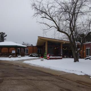 A winter scene featuring a modern building surrounded by snow and a tree.