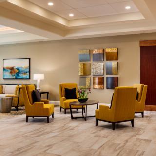 A modern lobby with yellow armchairs, decorative artwork, and a sleek design.