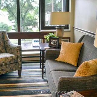A cozy living room with a sofa, armchair, and coffee table near a large window.