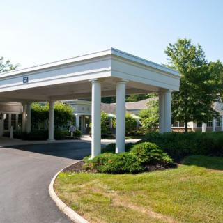 A building entrance with a covered driveway and landscaped surroundings.