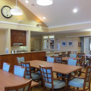 A cozy dining area with multiple tables and chairs arranged neatly under warm lighting.