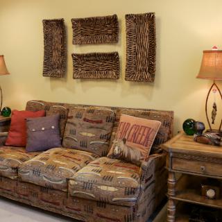 A cozy living room setup featuring a patterned couch, decorative art on the wall, and stylish lamps.