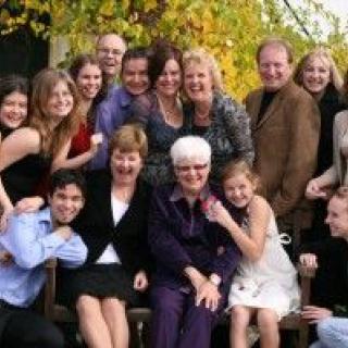 A joyful family gathering outdoors during autumn, with everyone smiling for the photo.