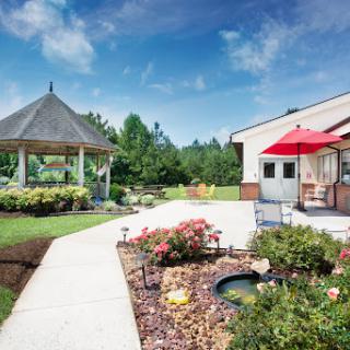 A peaceful garden setting featuring a gazebo, colorful flowers, and a clear blue sky.