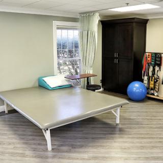 A well-equipped therapy room featuring a treatment table, fitness ball, and various exercise tools.