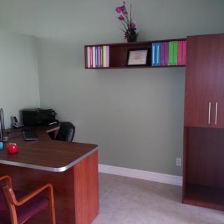 A tidy office space with a desk, chair, and bookshelf.