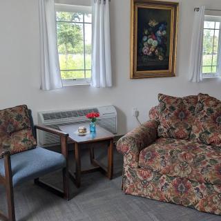 A cozy living room corner with a floral-patterned armchair, a small table, and a painting on the wall.