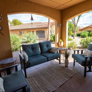 A cozy outdoor patio with cushioned seating and a rug under a covered porch.