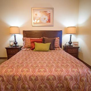 A cozy bedroom with a neatly made bed, flanked by two lamps on nightstands.