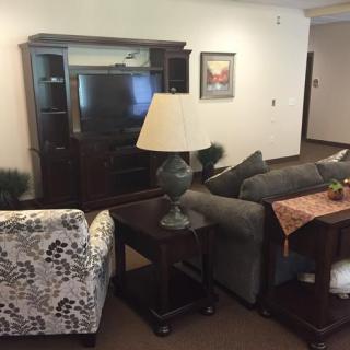 A cozy living room setup with a sofa, armchair, lamp, and TV stand.