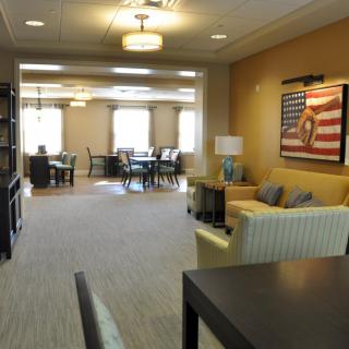 A spacious lounge area with comfortable seating, tables, and artwork on the wall.