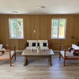 A minimalist living room with wood paneling, featuring a sofa, two chairs, and a coffee table.