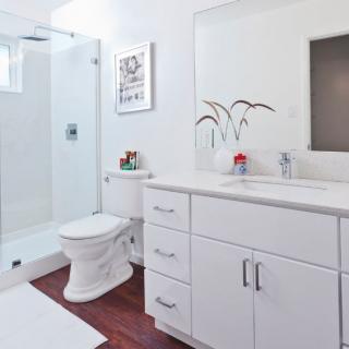 A modern white bathroom with a glass shower, sink, and cabinet.