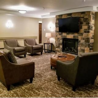 A cozy living room with armchairs, a fireplace, and a wall-mounted TV.