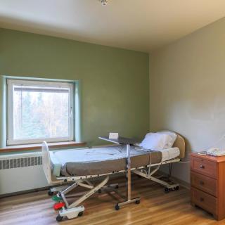 A hospital room with a single adjustable bed and a small bedside table.
