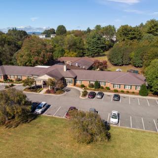 A serene aerial view of a facility surrounded by greenery and a spacious parking lot.