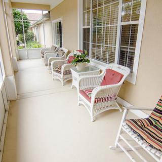 A cozy porch with wicker chairs and colorful cushions, adorned with potted plants.