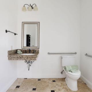 A modern bathroom with a granite sink, toilet, and stylish mirror.