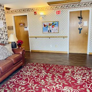 A cozy lobby area with a patterned carpet, couch, and decorated doors.