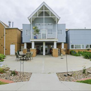 A modern building entrance with outdoor seating and landscaped surroundings.