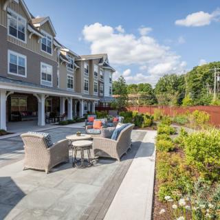 A beautifully landscaped outdoor patio area with stylish furniture and a multi-story residential building in the background.