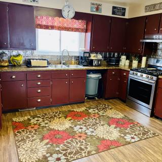 A cozy kitchen with dark cabinets and a colorful rug.
