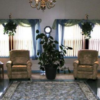A cozy living room setup with two chairs, indoor plants, and a chandelier.