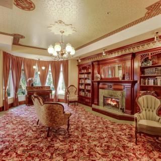 A vintage-style library room featuring antique furniture, a fireplace, and a decorative ceiling.