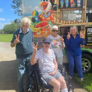 A group of elderly people enjoying a sunny day near an ice cream truck.