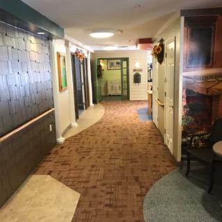 A well-lit hallway with carpeted flooring, decorated with artwork and various decor items.