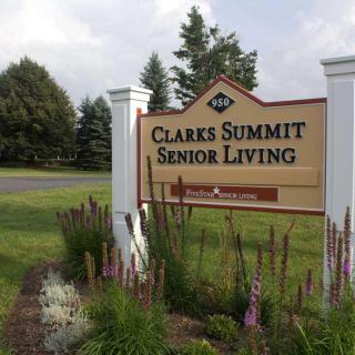Sign for Clarks Summit Senior Living surrounded by landscaped greenery.