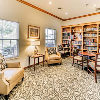 A cozy library with bookshelves, comfortable armchairs, and natural light streaming through the windows.