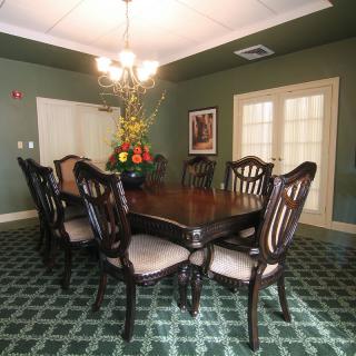 A well-decorated dining room featuring a large wooden table with chairs, a chandelier, and an elegant carpet.