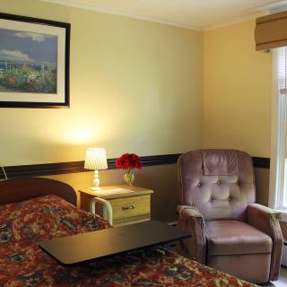 Cozy hotel room with a bed, lamp, and armchair.