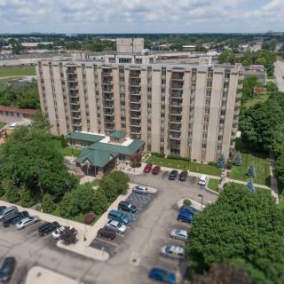 Aerial view of an apartment building with a parking lot and surrounding greenery.