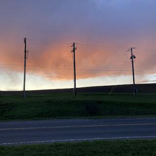 A serene evening landscape featuring power lines against a colorful sunset.