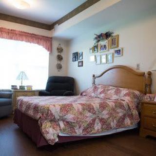 A cozy bedroom with a floral bedspread, armchair, and natural light coming through the window.