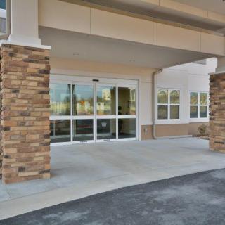 A modern building entrance with glass doors and stone pillar accents.