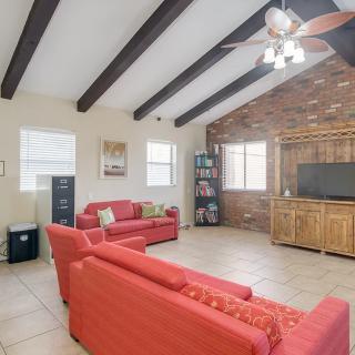 A cozy living room featuring red sofas, exposed wooden beams, and a brick accent wall with a television.